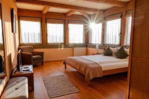 a bedroom with a bed and a chair and windows at Harmonia Mundi in Vlaha