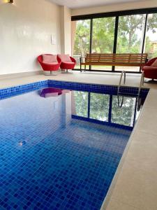 uma piscina com cadeiras vermelhas e um piso de azulejo azul em Pousada Flor de Anis em Alto Paraíso de Goiás