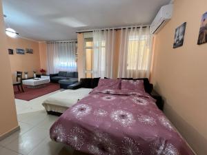 a bedroom with a purple bed and a living room at Elbasan center family apartment n.42 in Elbasan