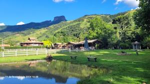 a park with a pond and buildings and a mountain at Chalés Poly in São Bento do Sapucaí