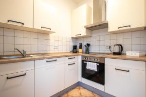 een keuken met witte kasten en een fornuis met oven bij StadtNatur Apartment am Küchwald - mit Balkon, Streaming-TV, Badewanne, Arbeitsplatz in Chemnitz