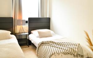 a bedroom with two beds and a window at MILPAU Bottrop 2 - Modernes und zentrales Premium-Apartment für 4 Personen mit Queensize-Bett und Einzelbetten - Netflix, Nespresso und Smart-TV in Bottrop