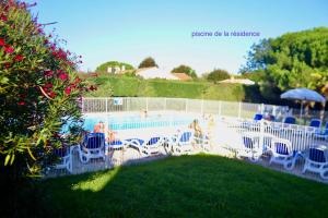 a swimming pool with chairs and an umbrella at Près des claires in Le Château-dʼOléron