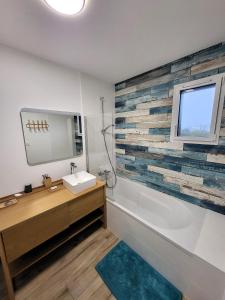 La salle de bains est pourvue d'un lavabo, d'une baignoire et d'une fenêtre. dans l'établissement TY COAT - Maison neuve avec vue mer, piscine et bain nordique, à Saint-Pabu