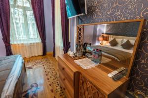 a bedroom with a bed and a wooden dresser with a desk at Prestige Prime Hotel in Baku