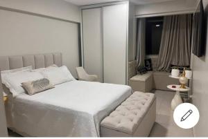 a bedroom with a large white bed and a chair at ESPAÇO ACONCHEGANTE NO SUDOESTE in Brasilia