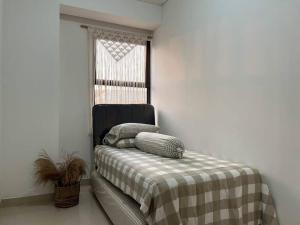 um quarto com uma cama com um cobertor xadrez e uma janela em Apt Transpark Cibubur 2 BR With Wi-Fi & Pool em Kalimanggis