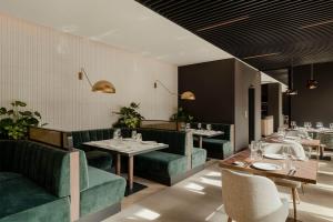 a restaurant with green couches and tables and chairs at VacationClub – Lwowska 2C Apartament 14 in Kołobrzeg