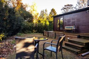 um pátio com 2 cadeiras, uma mesa e um banco em Veluwe cottage close to forest & wellness em Putten