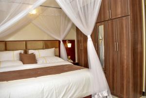 - une chambre avec un lit à baldaquin et des rideaux blancs dans l'établissement Jengel Studio Apartments Entebbe 1, à Entebbe