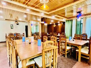 een eetkamer met houten tafels en stoelen bij The Kalinga Resort Manali - Heaven In Mountains in Manāli