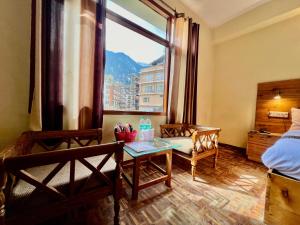 een kamer met een bed, een tafel en een raam bij The Kalinga Resort Manali - Heaven In Mountains in Manāli