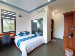 1 dormitorio con cama, escritorio y ventana en Khe Sanh Luxury Hotel, en Hương Hóa
