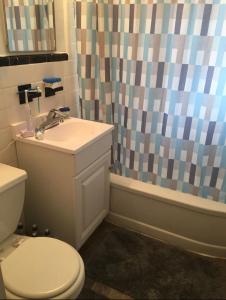 a bathroom with a toilet and a shower curtain at Suite 55 in Elmwood Park