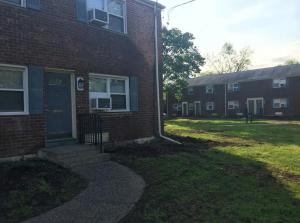 a brick building with a blue door and a grass yard at Suite 55 in Elmwood Park