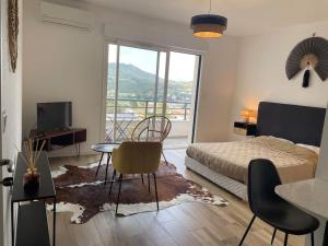 a bedroom with a bed and a table and chairs at Magnifique Studio dans Résidence neuve in Corte