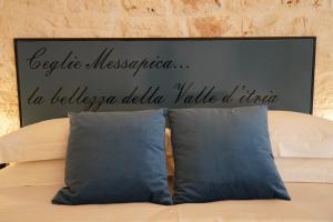 ein Schild an einer Wand über einem Bett mit zwei Kissen in der Unterkunft La Suite del Conte - STORIA, CONFORT ed ELEGANZA in Ceglie Messapica