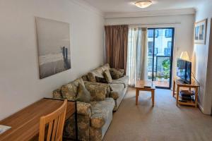 una sala de estar con un sofá y una mesa en City & lakeside with pool, gym & tennis court, only 15 mins walk into the City, en Perth