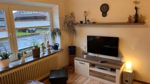 ein Wohnzimmer mit einem Flachbild-TV und einem Fenster in der Unterkunft Ferienhaus Wilhelmshaven Voslapp 78 in Wilhelmshaven
