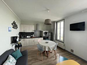a living room with a table and a kitchen at Superbe appartement front de mer in Luc-sur-Mer