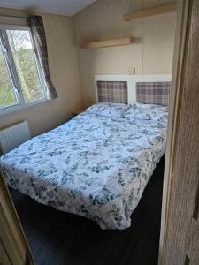 a bedroom with a bed with a blue and white comforter at 113 Caravan at meadow lakes in St Austell
