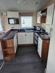 a small kitchen with white cabinets and a sink at 113 Caravan at meadow lakes in St Austell