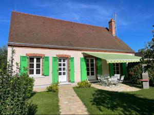 a house with green shutters and chairs in the yard at Gîte du canal rue de la Tuilerie in Amilly