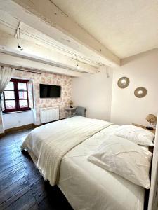 Un dormitorio con una gran cama blanca y una pared de ladrillo en L'abri-côtier, en Saint-Suliac