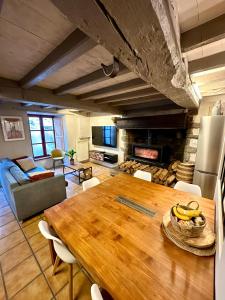 L'abri-côtier في سانت - سولياك: مطبخ وغرفة معيشة مع طاولة خشبية ومدفأة