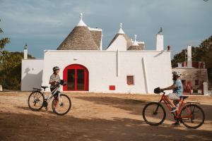 two people riding bikes in front of a building at i Trulli di Figazzano in Locorotondo