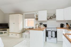a kitchen with white cabinets and a counter top at Stylish and homely 1 bed Edwardian Coach House in Colchester