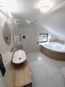 a bathroom with a sink and a tub and a toilet at Szafran Home Spa in Korbielów