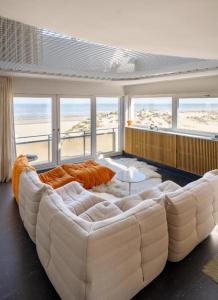 um grande sofá branco numa sala de estar com vista para a praia em Vista del Mar Sixties em Koksijde