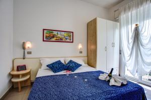 a bedroom with a bed with blue sheets and a window at Hotel Tiziana in Rimini