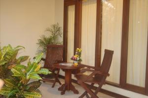 a wooden table and chairs on a balcony with plants at Gunakaya Homestay in Sanur