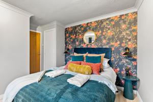 1 dormitorio con cama azul y papel pintado con motivos florales en Unique Cambridgeshire Gem, en Fulbourn