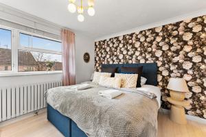 a bedroom with a blue bed with a floral accent wall at Unique Cambridgeshire Gem in Fulbourn