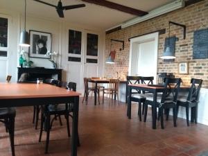 a dining room with tables and chairs and a brick wall at Chambre d'hôtes L'Ermite in Saint-Algis