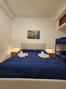 a bedroom with a blue bed with two white pillows at Clary Home Cefalu' in Cefalù