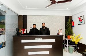 two men standing behind a counter in a room at Mirage Grand in McLeod Ganj