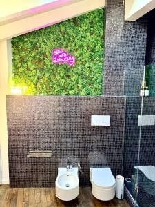 a bathroom with a toilet and a wall with plants at [Bridge Apt.] Garage - Netflix - wifi in Brescia