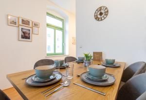 a dining room table with chairs and a clock on the wall at StadtNatur Apartment am Küchwald - mit Balkon, Streaming-TV, Badewanne, Arbeitsplatz in Chemnitz