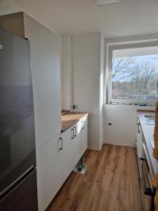uma cozinha com armários brancos e uma janela em ruhige Privatzimmer im Apartment Natur Messe Zentral em Düsseldorf