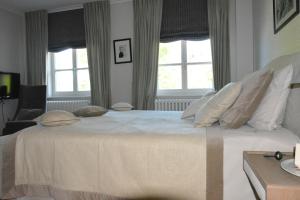 a bedroom with a large white bed with windows at B & B Landhuis Ter Velt in Melle