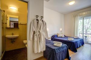 a hotel room with two beds and a sink at Hotel Tiziana in Rimini