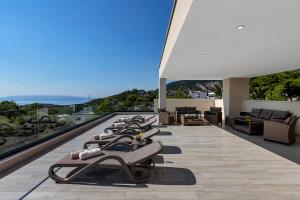 a row of chaise lounges are lined up on a balcony at Luxury Villa Bašak with Infinity Pool and Sea View in Makarska