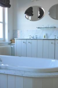 a white bathroom with a tub and a mirror at B & B Landhuis Ter Velt in Melle