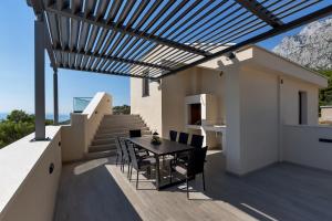 a patio with a table and chairs under a pergola at Luxury Villa Bašak with Infinity Pool and Sea View in Makarska +15 photos
