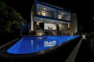 a house with a swimming pool at night at Luxury Villa Bašak with Infinity Pool and Sea View in Makarska