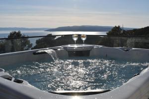 a hot tub with two glasses of wine at Luxury Villa Bašak with Infinity Pool and Sea View in Makarska